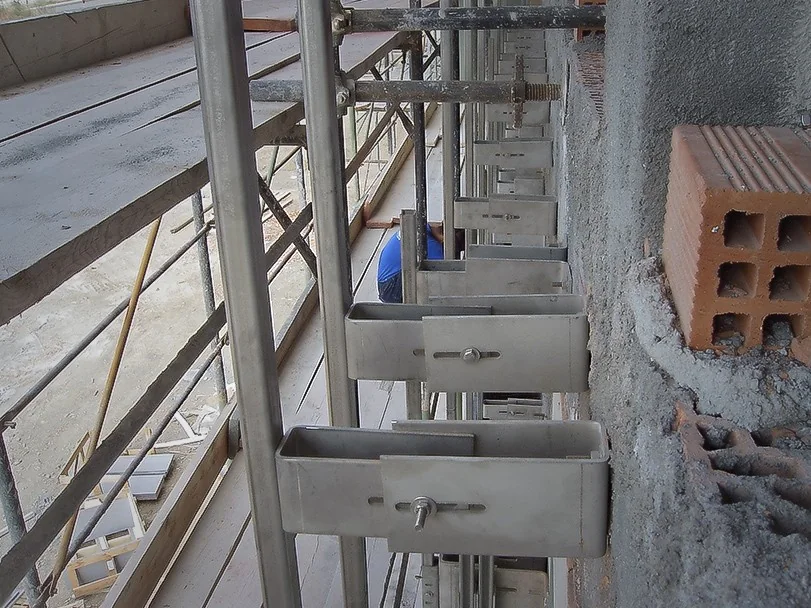 Stainless steel sub-structure brackets set out along the backup wall on site, forming the ventilated cavity before the stone panels are hung