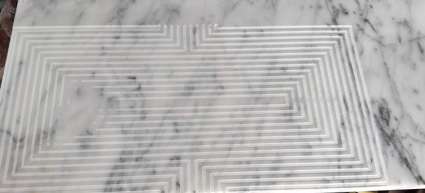 CNC fretwork engraving freshly machined on a white marble panel