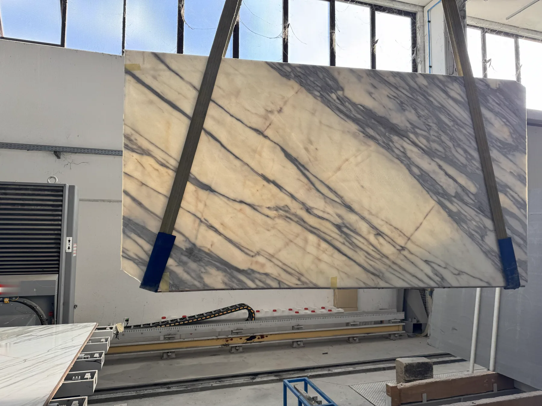 Calacatta marble slab hoisted in the workshop during selection for a vein-matched master bath