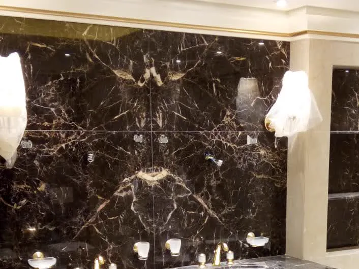 Book-matched dark marble feature wall, the four panels mirrored on the vertical and horizontal joints
