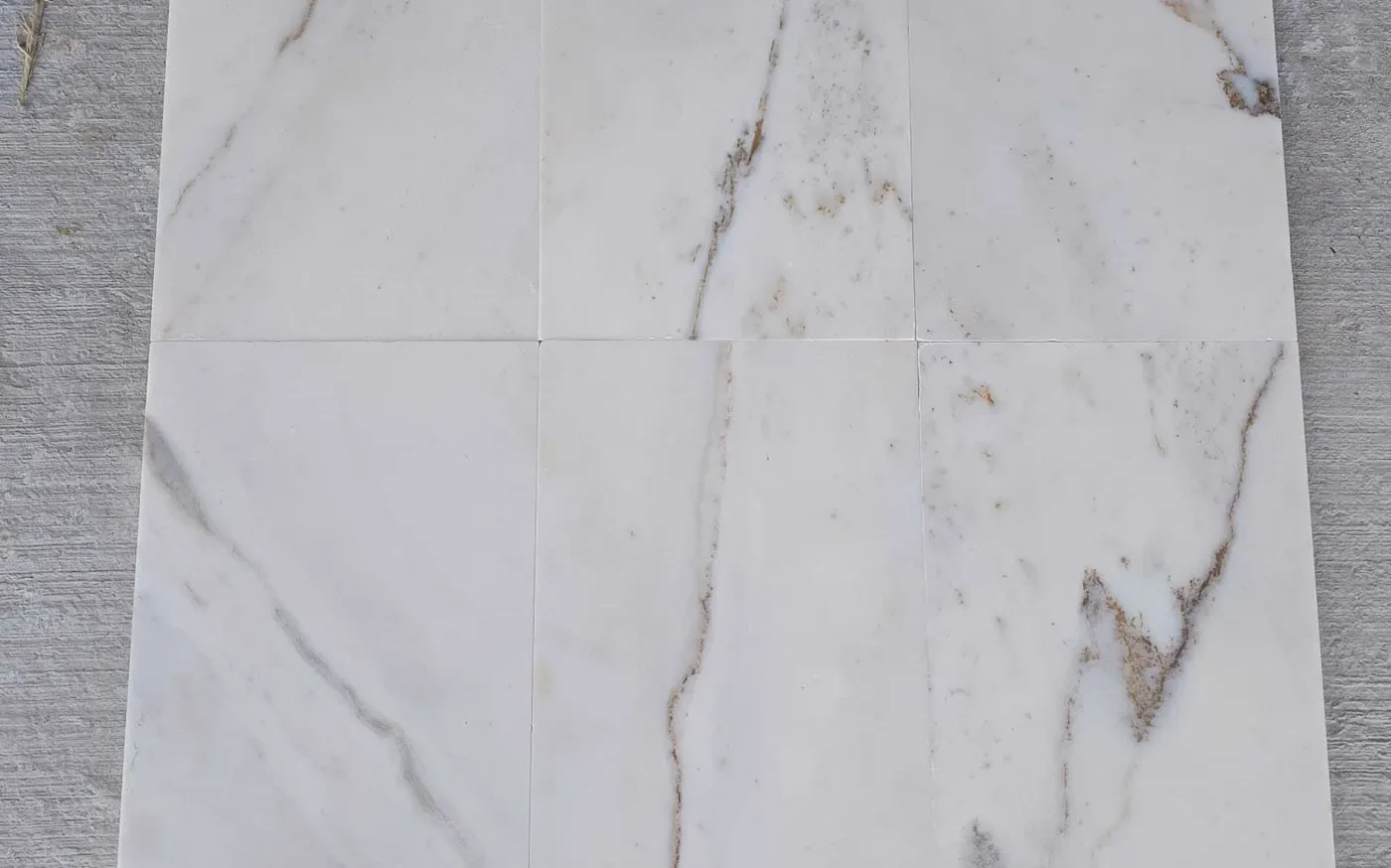 White marble tiles dry-laid on the ground in sequence to check the vein match before cutting