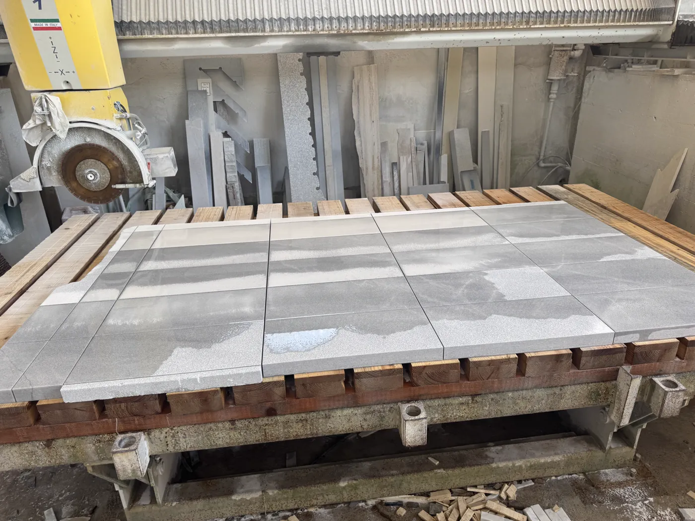 Freshly cut gray stone pavers on the bridge saw bench, still wet from the blade