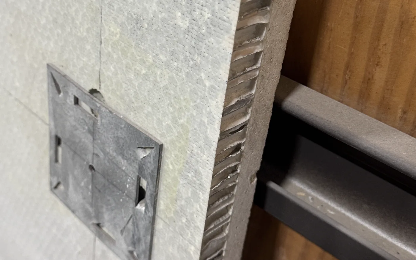 Back of a stone honeycomb facade panel: aluminum honeycomb core visible at the edge, thin stone face and interlocking clip plate