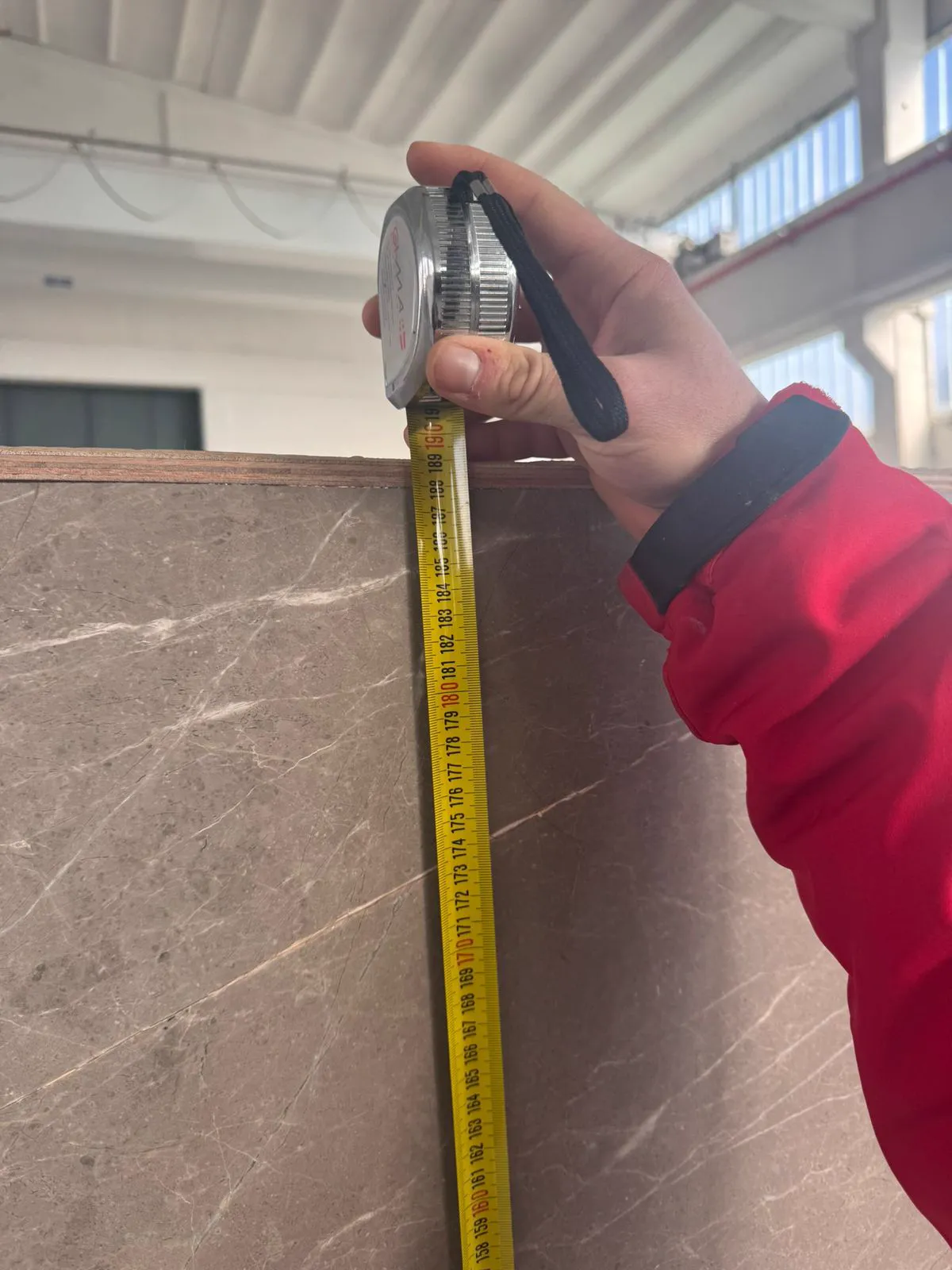 Operator checking the height of a stone panel with a tape measure before release