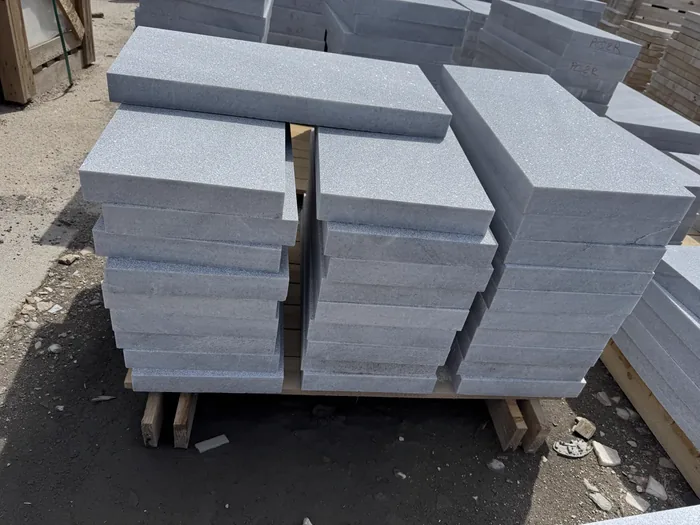 Grey stone copings stacked on a pallet in the yard
