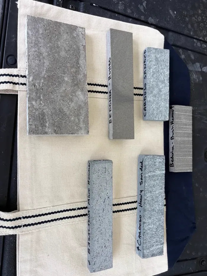 Six labelled finish samples of the same stone laid out on a cloth