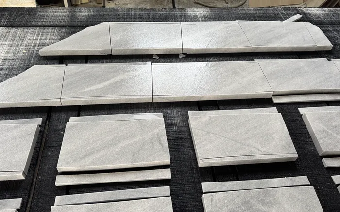 Profiled coping runs and square deck pieces laid out on the fabrication bench for a dimension check