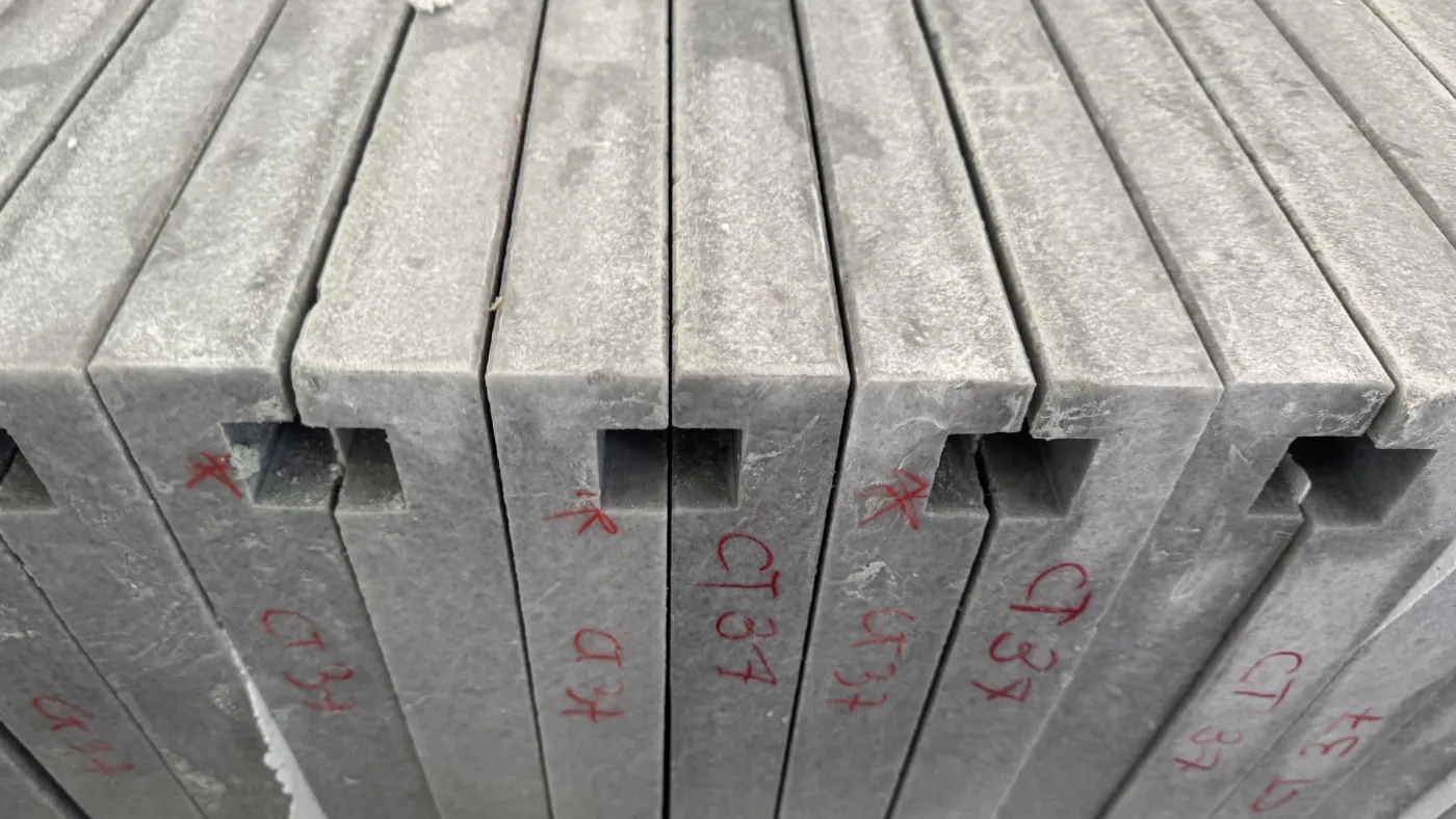 Finished grey stone copings on edge with the drip kerf cut and hand piece marks