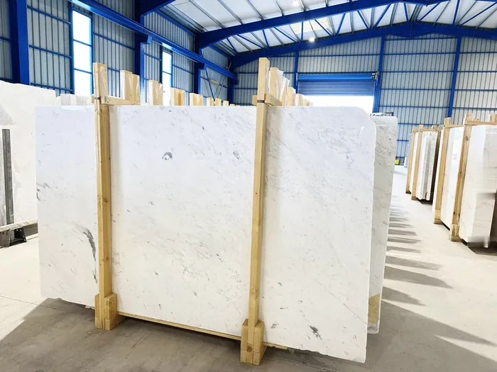 Rows of white marble slabs on wooden racks in a bright warehouse