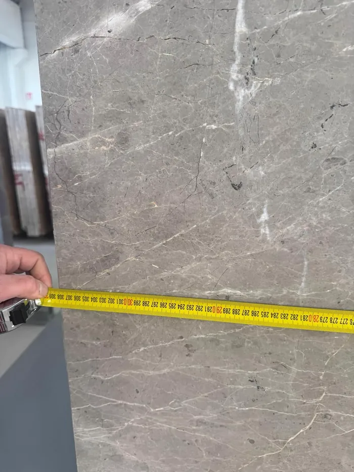 Tape measure reading over 300 cm against a grey veined slab during inspection