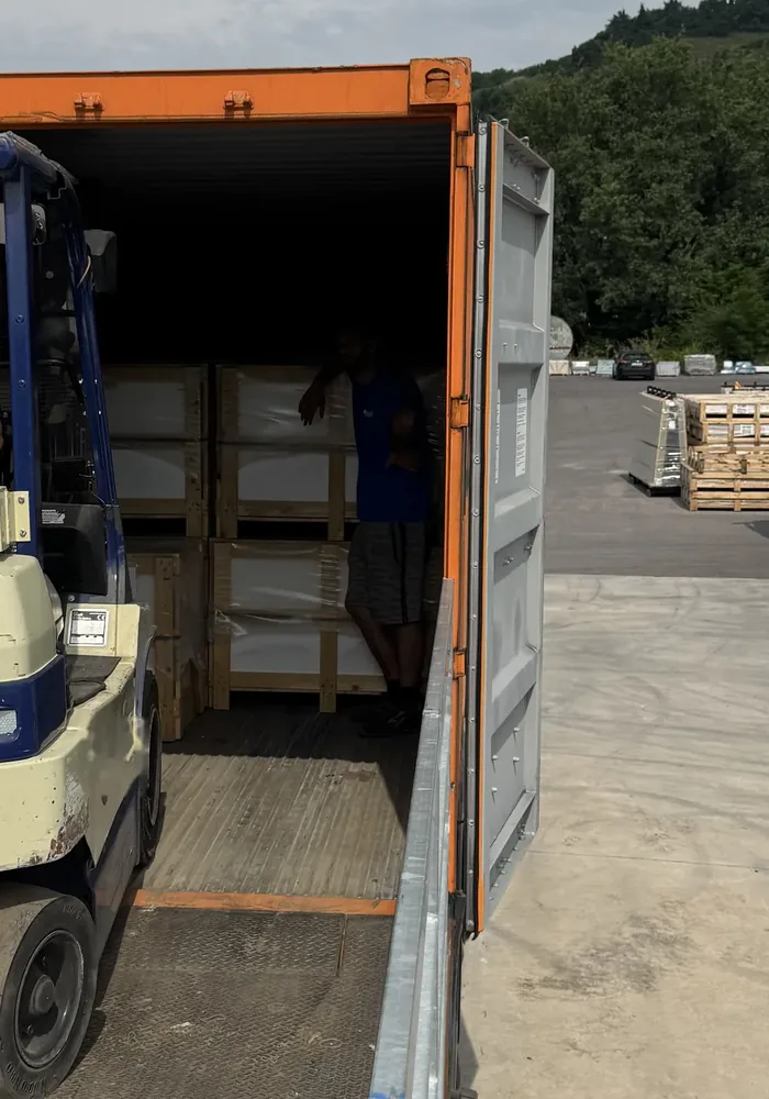 Forklift loading a crate into an open shipping container