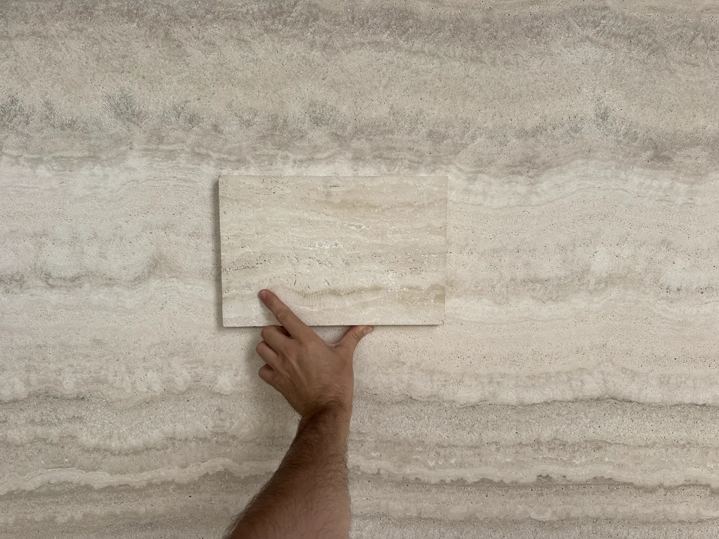 Hand holding a stone sample centered on the matching mother slab