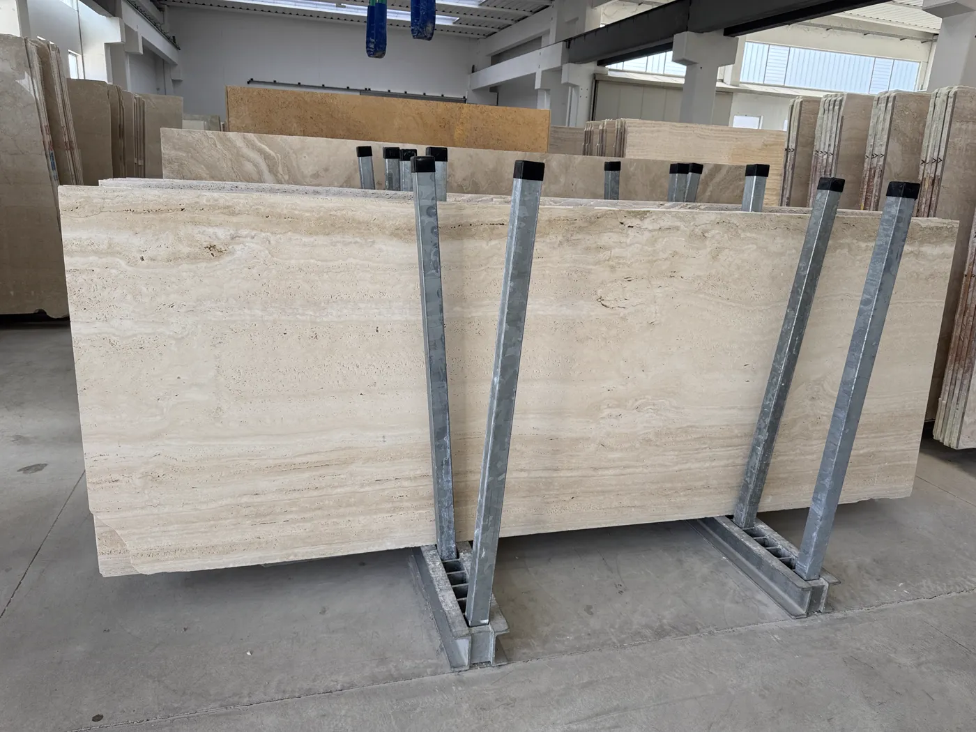 Racks of vein-cut travertine slabs lined up in the warehouse