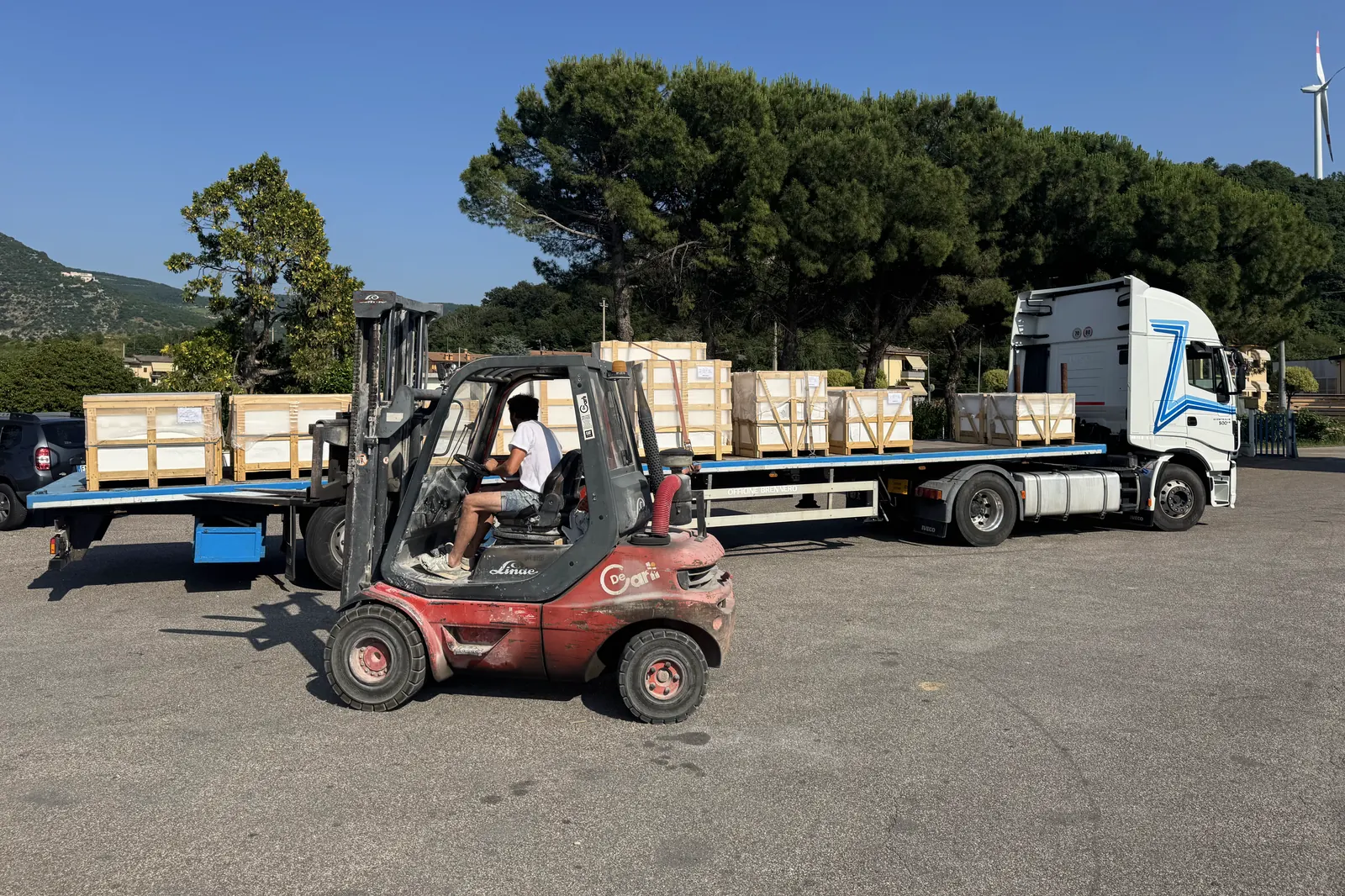 Flatbed truck loaded with export crates of finished stone, forklift in maneuver