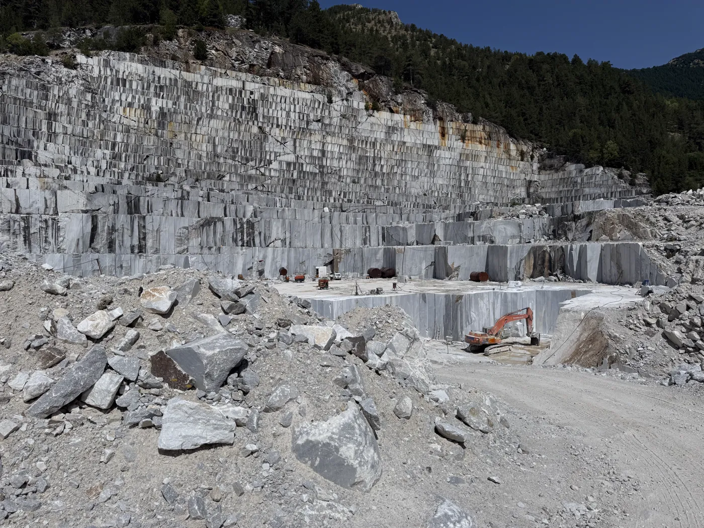 Stepped quarry benches with an excavator at work