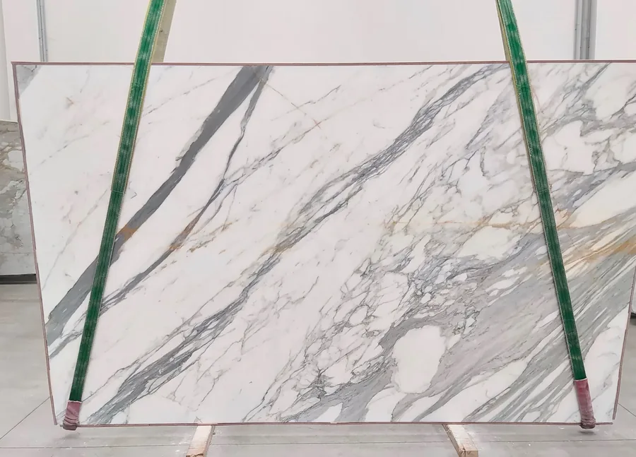 White Calacatta Gold marble slab on the rack, grey and gold veining running across the face
